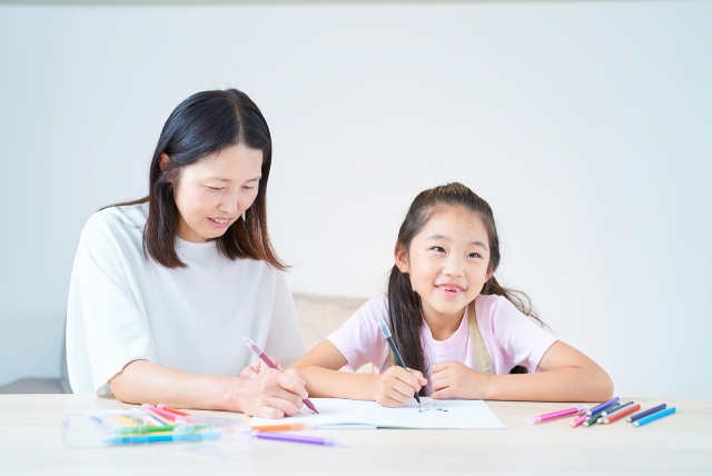 何かを書く女性と少女